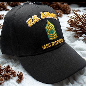 Puede incluir: Gorra de béisbol negra con texto bordado en oro "U.S. ARMY" y una insignia verde y dorada. El texto "MSG RETIRED" está bordado en oro. La gorra está sobre una superficie nevada.