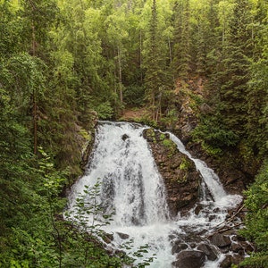 Waterfall in the green trees and rocks in Anchorage, Alaska