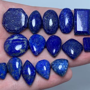 Puede incluir: Una colección de catorce piedras preciosas de lapislázuli pulidas en varias formas, incluyendo cortes octogonales, ovalados, rectangulares, de pera y triangulares. Cada piedra de color azul profundo presenta inclusiones naturales de pirita dorada.