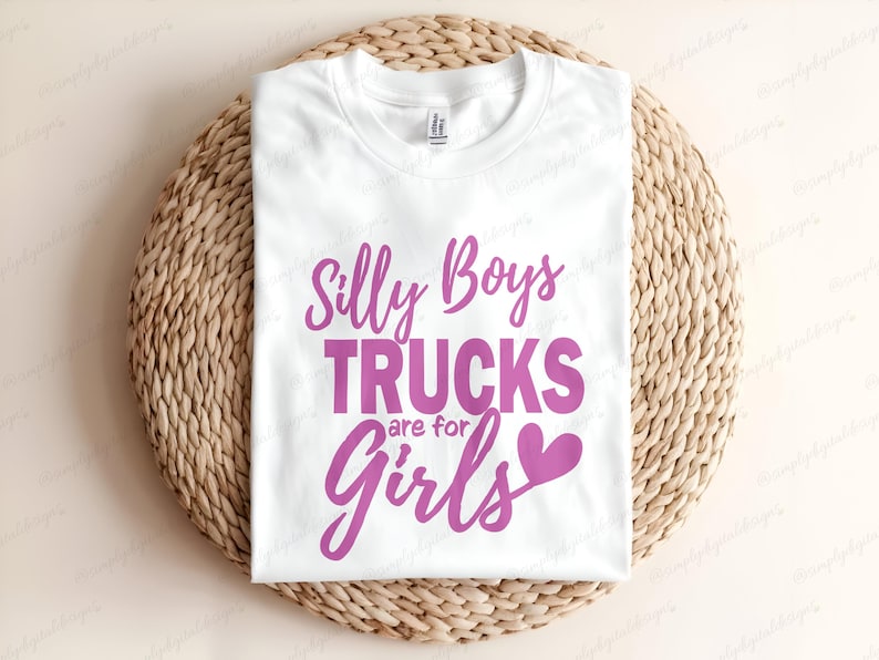 Op de afbeelding: Wit T-shirt met roze tekst die "Silly Boys Trucks are for Girls" met een roze hartje zegt.