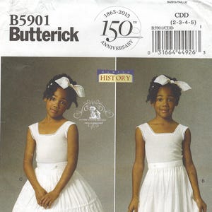 Op de afbeelding: Butterick patroon B5901 voor historische meisjeskleding. Het patroon bevat een witte jurk en broek ensemble. De afbeelding toont twee jonge meisjes die de outfits dragen. Het patroon viert de 150e verjaardag.