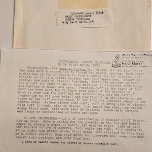 May include: A vintage sewing pattern for an undersleeve and sleeve crinoline, dated 1983. The pattern includes instructions and measurements for creating the garment. The paper is aged with text and a label.