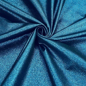 Puede incluir: Primer plano de una tela de color verde azulado con una superficie brillante y texturizada. La tela está doblada y drapeada, creando un patrón arremolinado con luces y sombras. El material parece ser un textil lujoso.
