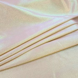May include: A close-up of iridescent white fabric with a subtle sparkle. The fabric is folded and draped, showcasing its texture and sheen.