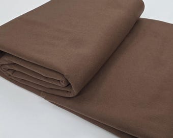 May include: Folded brown fabric, possibly a textile or material for crafting. The fabric is a solid, warm brown color, with a soft, matte texture. The folds create shadows and depth, highlighting the fabric's thickness and drape.