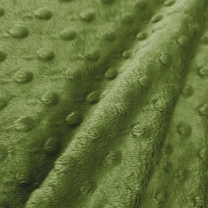 Könnte beinhalten: Nahaufnahme eines weichen, olivgrünen Stoffes mit einer strukturierten, genoppten Oberfläche. Das Plüschmaterial ist gefaltet, wodurch Schatten und Glanzlichter entstehen, die die taktile Qualität des Textils hervorheben. Die Farbe des Stoffes ist einheitlich.