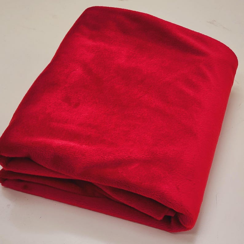 May include: A folded red fleece fabric. The fabric is soft and plush.