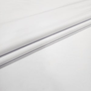 May include: White fabric with a smooth texture. The fabric is folded in half, creating a crease down the center.
