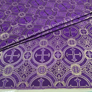May include: Purple fabric with a repeating pattern of gold crosses in circles. The fabric has a subtle sheen and a textured surface.