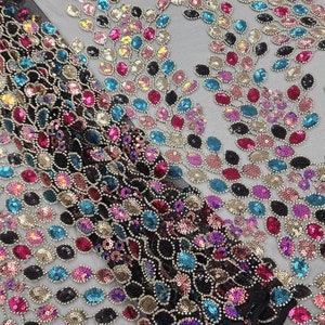 Puede incluir: Tela de malla negra con lentejuelas de colores en forma de hoja.