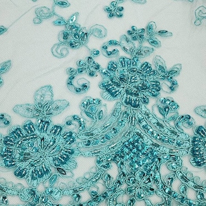 Puede incluir: Tela de encaje de cuentas turquesa con un diseño floral. El encaje tiene un patrón delicado e intrincado con pequeñas cuentas en todas partes.
