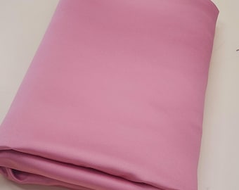May include: A folded, solid pink fabric, likely a textile or material for crafting or sewing. The fabric has a smooth, even texture and a soft, muted pink color. The edges are neatly folded, suggesting it is a new, unused piece of fabric.