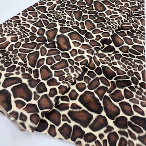 May include: Brown and cream faux fur fabric with a giraffe print pattern.