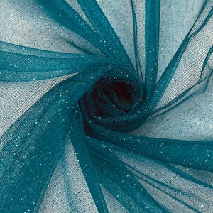 Könnte beinhalten: Ein türkisfarbener, transparenter Tüllstoff mit feiner Netzstruktur und einer verstreuten Glitzerbeschichtung. Das Material ist zu einer zentralen Spirale gerafft, was die Transparenz des Stoffes und das Funkeln des Glitzers hervorhebt.