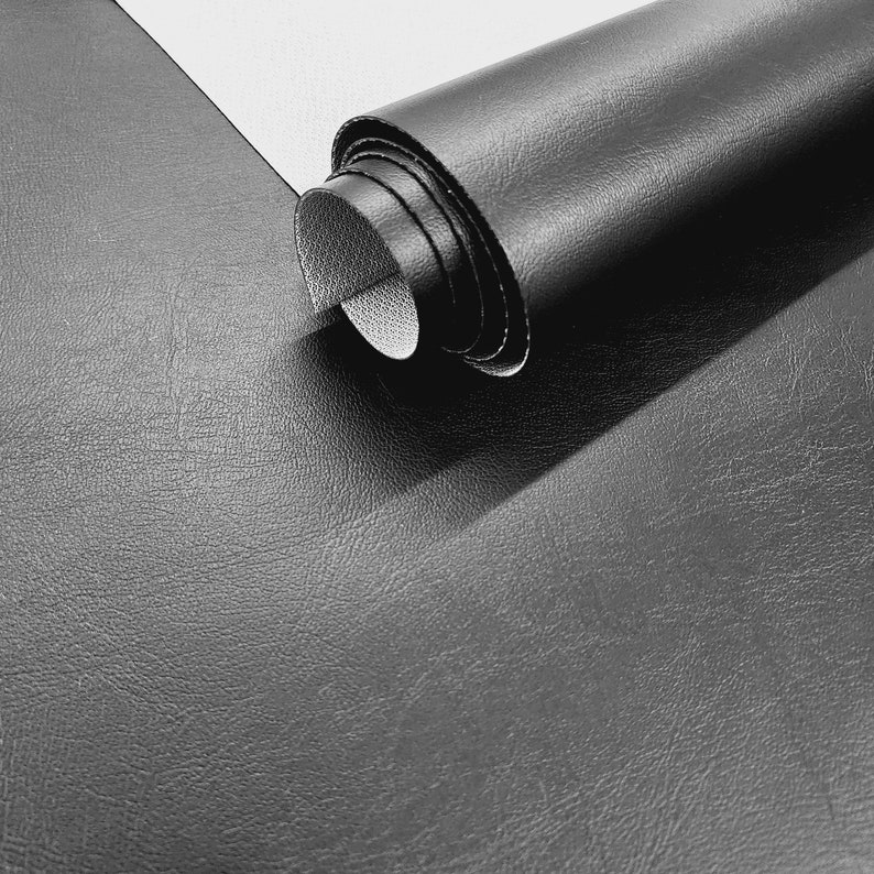 May include: Close-up of a rolled-up piece of black leather fabric. The fabric has a textured surface and is rolled up tightly.
