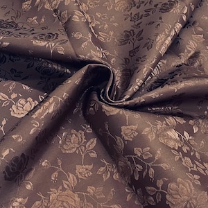 Puede incluir: Primer plano de una tela marrón con un estampado floral de rosas. La tela está drapeada, mostrando la textura y el diseño de las rosas y las hojas. El color es un marrón profundo y rico con acentos marrones más claros.