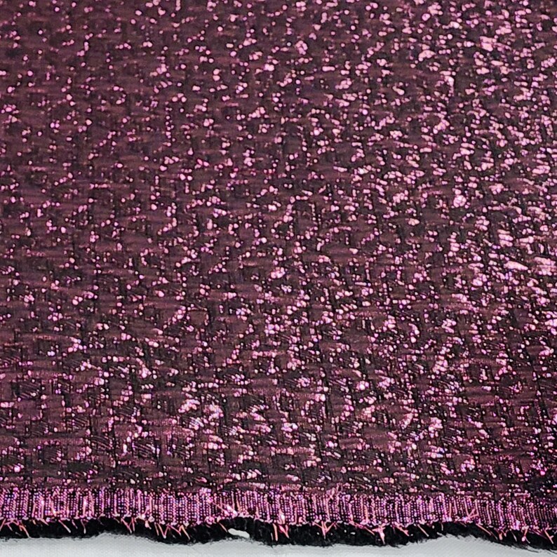 May include: Close-up of a deep purple fabric with a textured, woven pattern. The fabric has a subtle shimmer and a slightly raised edge.