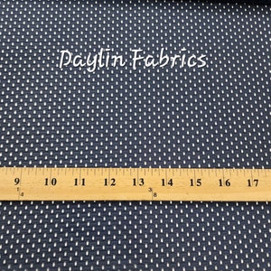 May include: Close-up of a navy blue fabric with a white polka dot pattern. A ruler is placed on top of the fabric, showing measurements from 8 to 18 inches.