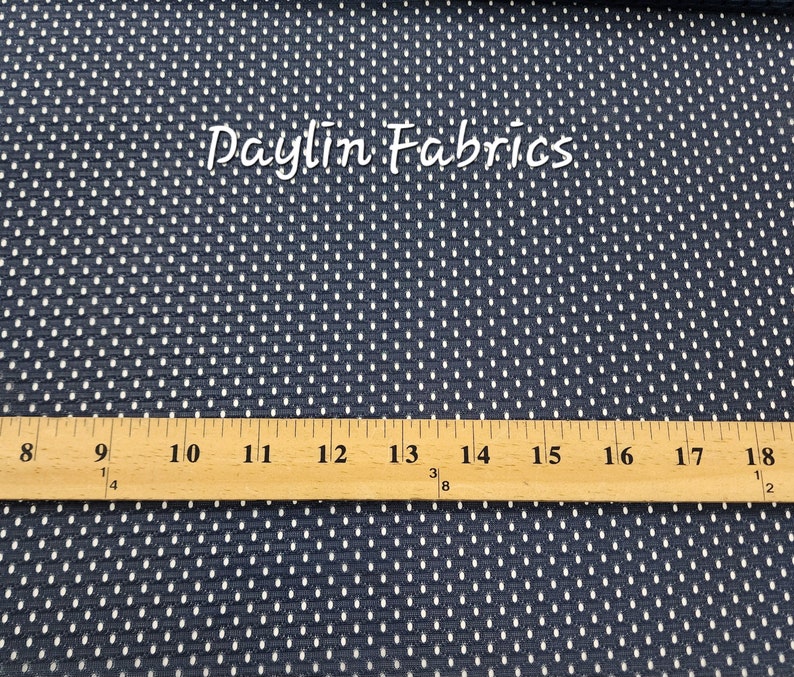 May include: Close-up of a navy blue fabric with a white polka dot pattern. A ruler is placed on top of the fabric, showing measurements from 8 to 18 inches.