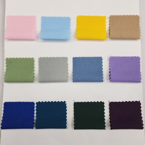 May include: A collection of 12 fabric swatches in various colors, including pink, light blue, yellow, beige, green, gray, blue, purple, dark blue, teal, dark green, and purple.