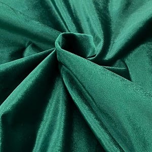 May include: A close-up of a deep green velvet fabric, showing its soft texture and rich color.