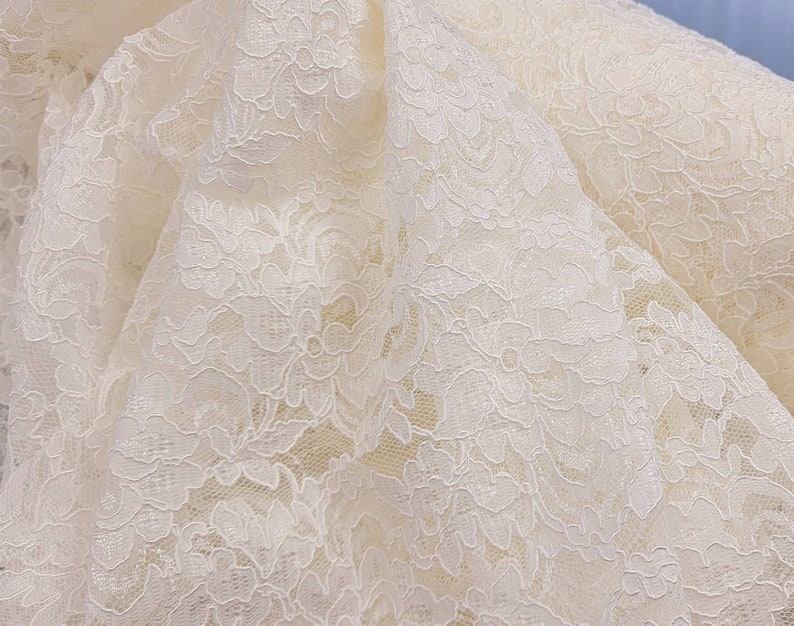 May include: White lace fabric with a delicate floral pattern.