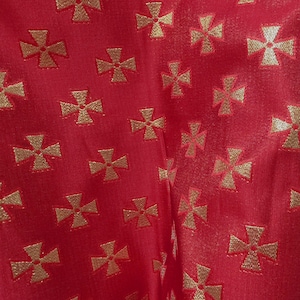 May include: Close-up of a red fabric with a repeating pattern of gold crosses. The fabric has a slight sheen, and the crosses are evenly spaced across the surface. The design is likely for a religious or historical themed item.