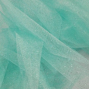 May include: A close-up of a light turquoise tulle fabric with a subtle sparkle. The fabric is soft and delicate, with a fine mesh weave.