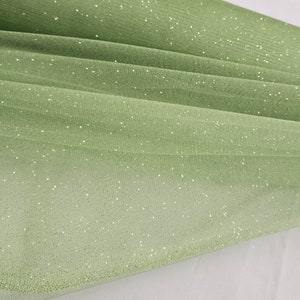 May include: A pale green tulle fabric with a subtle sparkle. The fabric is soft and sheer, and it has a delicate texture.