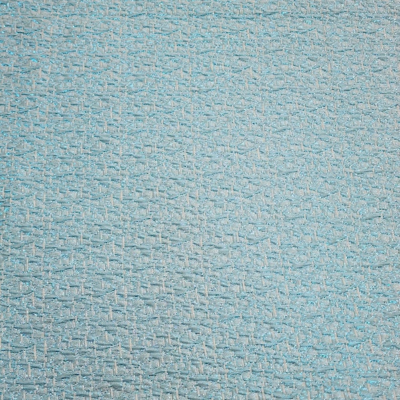 May include: A close-up of a light blue textured fabric with a woven pattern.