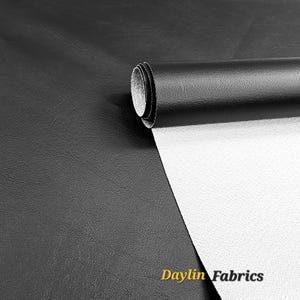 Puede incluir: Tela de imitación de cuero negro con respaldo blanco. La tela está enrollada y la etiqueta "Daylin Fabrics" es visible.