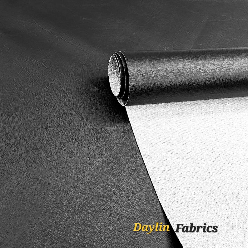 May include: Black faux leather fabric with a white backing. The fabric is rolled up and the label "Daylin Fabrics" is visible.