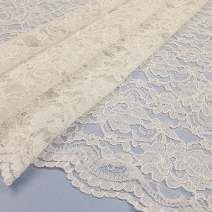 May include: White lace fabric with a delicate floral pattern. The lace is soft and sheer, and it would be perfect for a variety of crafting projects.