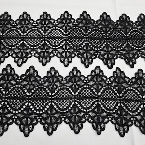 May include: Black lace trim with a scalloped edge and intricate floral pattern. The lace is delicate and has a soft, flowing texture.