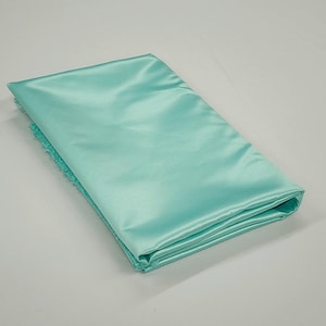 May include: A folded piece of light blue satin fabric. The fabric is smooth and shiny.