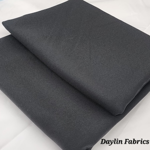以下が含まれることがあります： 黒色の布地が2枚重ねられています。布地は微妙な質感で、滑らかな仕上がりです。画像の右下隅に「Daylin Fabrics」というテキストが表示されています。