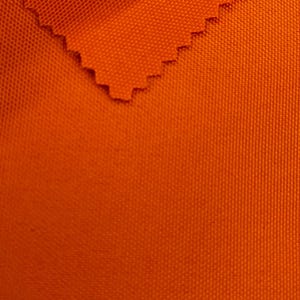 以下が含まれることがあります： 質感のある織り目の明るいオレンジ色の布のクローズアップ。布は折り畳まれており、裏側が見える。