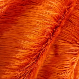 Op de afbeelding: Close-up van een feloranje nep bontstof. De vacht is zacht en pluche, met een lichte glans.