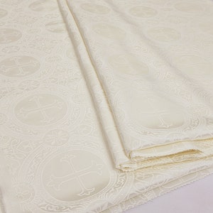May include: White fabric with a repeating pattern of a cross in a circle. The fabric is folded in thirds.