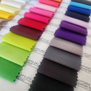May include: A fabric swatch book with a variety of colors, including red, green, purple, and gray. The swatches are labeled with their corresponding color names and codes.