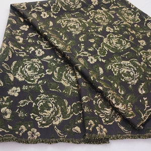May include: A dark brown fabric with a green and gold floral pattern. The fabric has a textured, raised design.