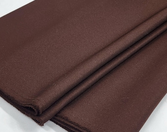 May include: A close-up of a brown fabric with a smooth, slightly shiny texture. The fabric is folded in half, showing the edges.