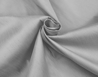 May include: A close-up of a smooth, silver fabric with a soft, flowing texture. The fabric is draped and folded, creating a gentle, elegant curve.
