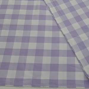 Puede incluir: Primer plano de una tela con un patrón de cuadros grandes en lavanda y blanco. La tela está doblada, mostrando el patrón en ambos lados. Los bordes de la tela son visibles.