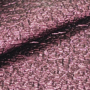 May include: Close-up of a pink and black textured fabric with a metallic sheen. The fabric has a woven pattern and a slightly iridescent finish.