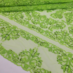 Puede incluir: Tela bordada verde lima con un patrón floral y lentejuelas. La tela tiene una textura transparente y de malla.