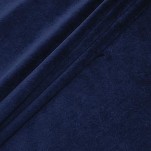 May include: Close-up of a deep navy blue fabric with a soft, velvety texture. The fabric is draped, creating folds and shadows that highlight its plush appearance. The text "Daylin Fabrics" is visible in the bottom right corner.