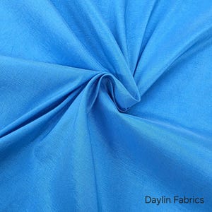 May include: A close-up of a light blue fabric with a subtle sheen. The fabric is smooth and has a slight texture. The fabric is folded in a way that shows its drape and flow.