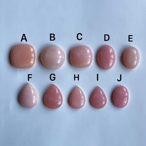 May include: Ten pink opal cabochons in various shapes and sizes, labelled A through J. The cabochons are arranged in two rows, with the top row containing square and rectangular shapes and the bottom row containing teardrop shapes.