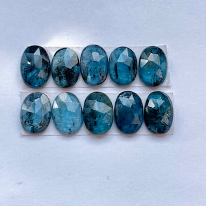 May include: Ten oval-shaped, faceted gemstones with a blue-green hue. The stones are arranged in two rows of five on a white background.